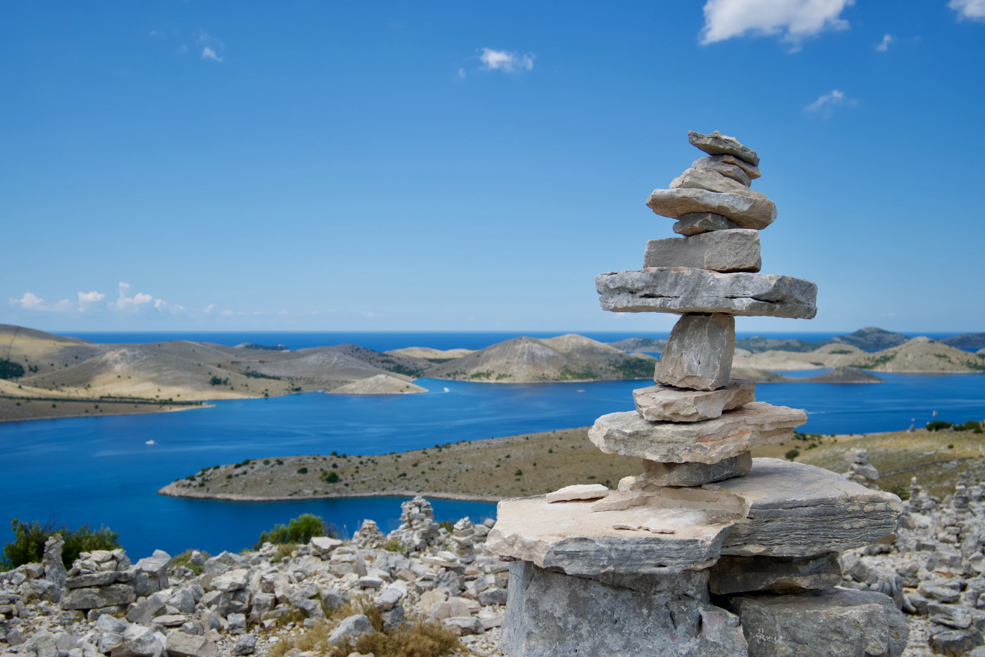 A stone cairn on a hilltop above the Kornati islands and blue channels, seen from the island of Žut