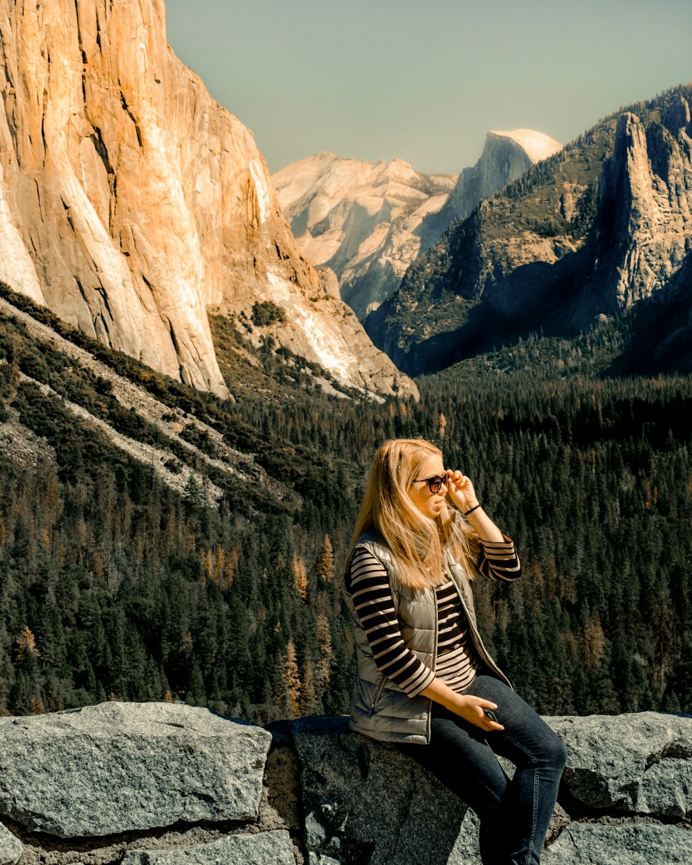 woman in black and white stripe long sleeve shirt sitting on rock formation during daytime