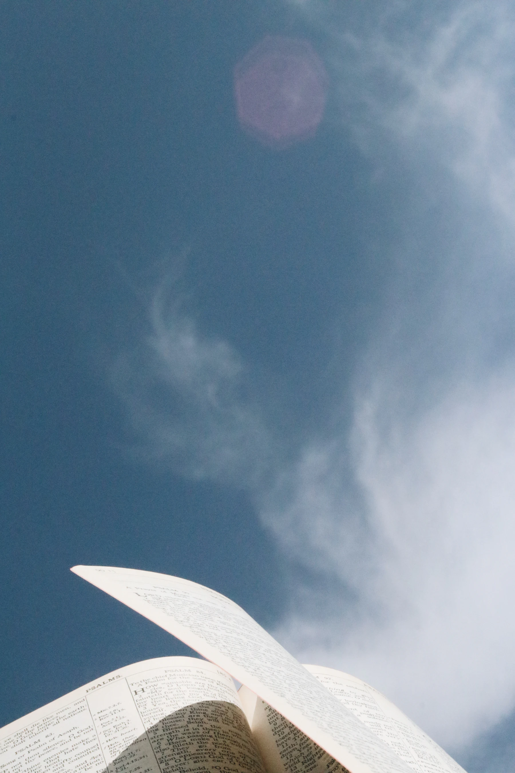 An open book held against a bright blue sky
