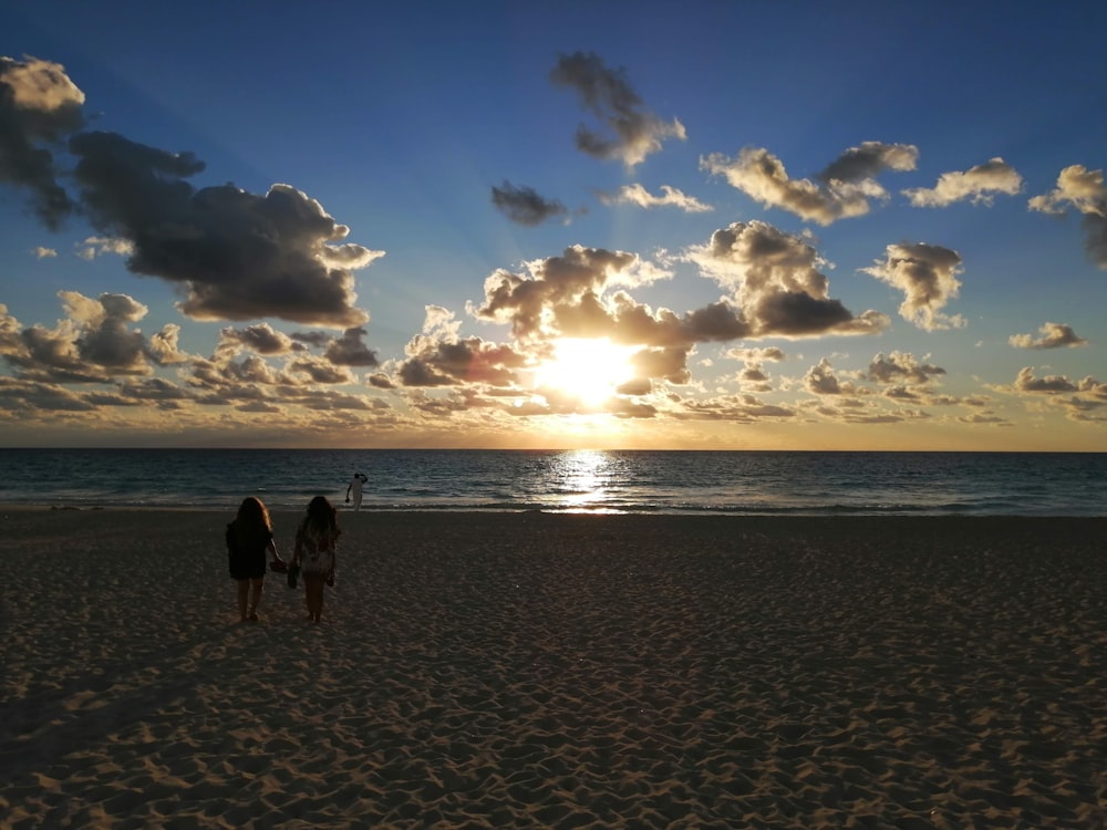 2 Personen spazieren am Strand während des Sonnenuntergangs
