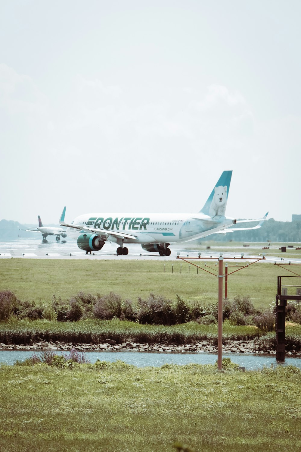 Weißes Passagierflugzeug tagsüber auf grünem Rasenfeld