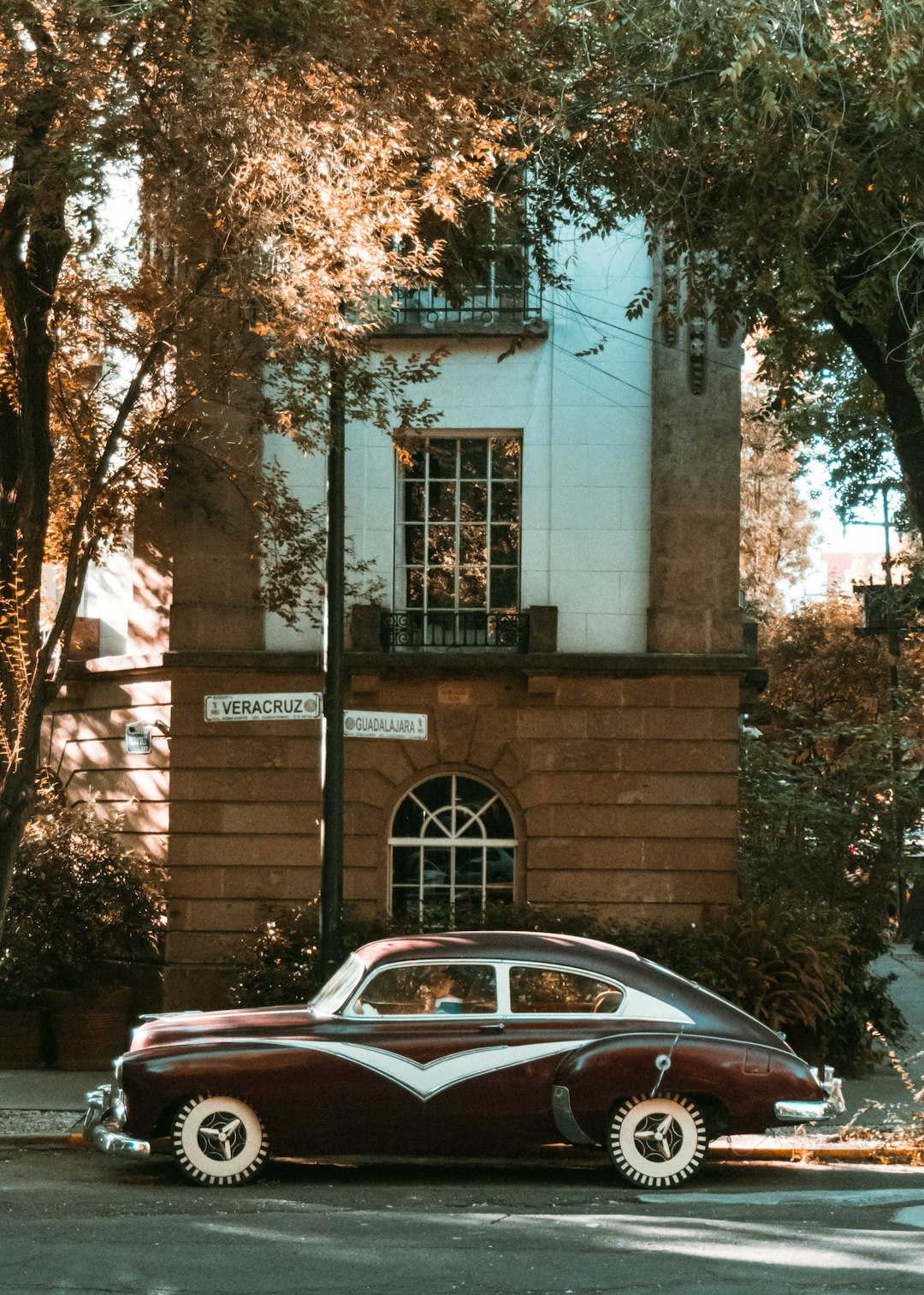 red car parked beside brown concrete building during daytime