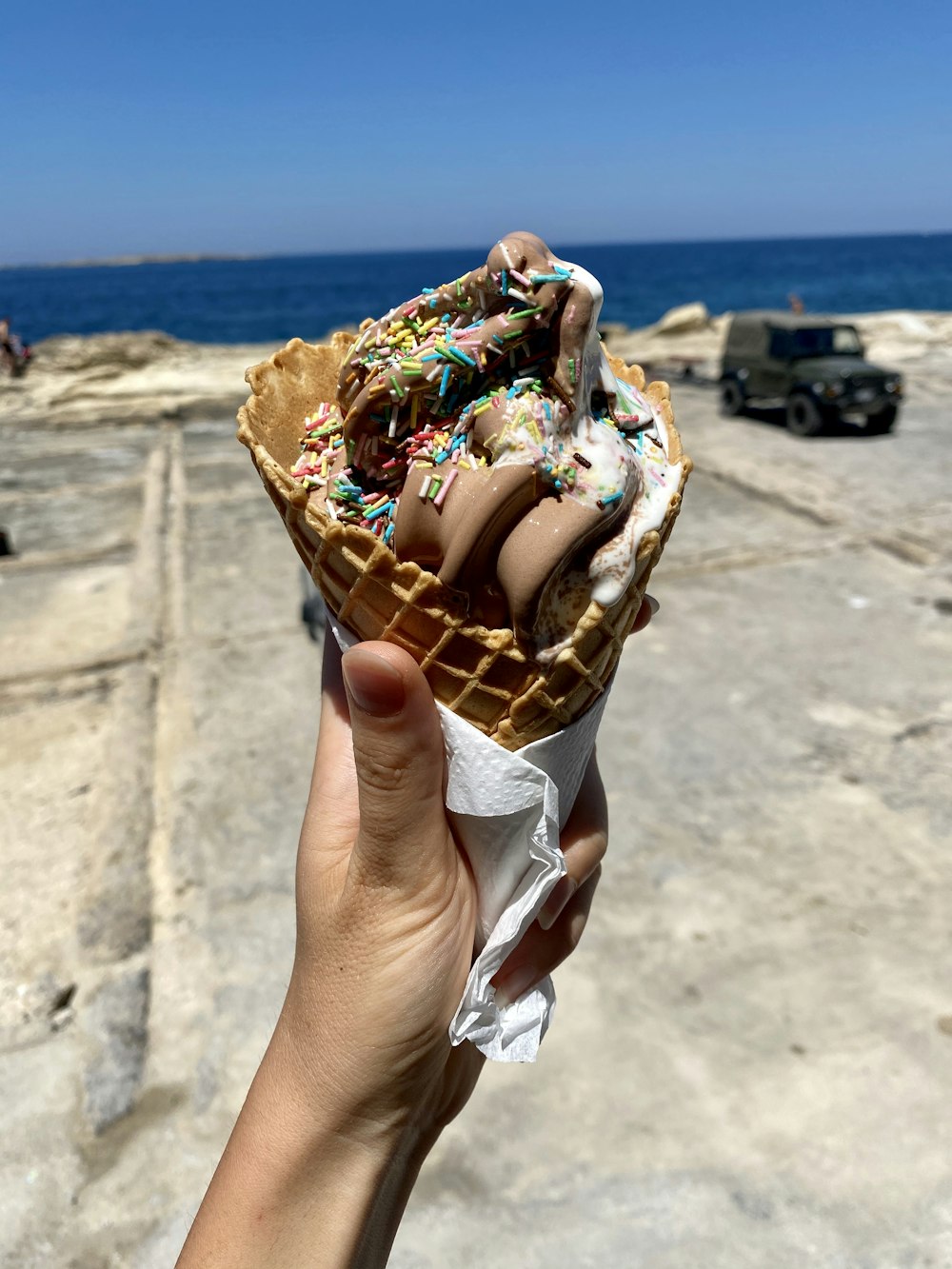 persona sosteniendo cono de helado con helado de chocolate y fresa