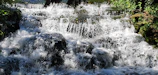 Refreshing Bhalu Gaad waterfall cascading over mossy stones surrounded by forest.