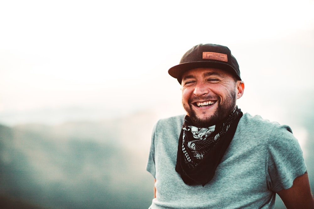 Hombre sonriente con suéter gris con gorra negra