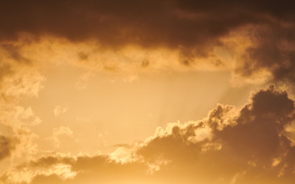 a plane flying through a cloudy sky at sunset