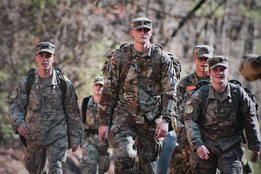 homens em uniforme de camuflagem em pé no campo durante o dia