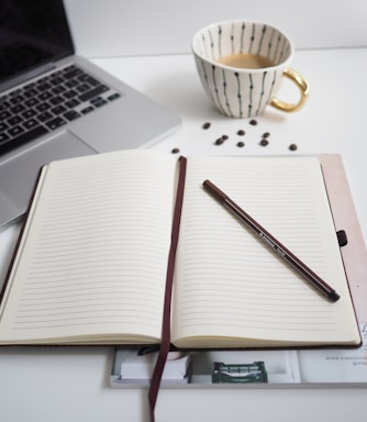 white notebook beside silver macbook pro