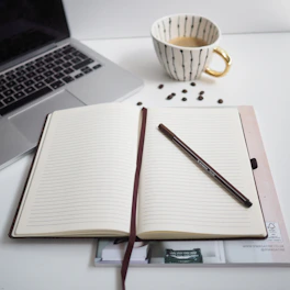 white notebook beside silver macbook pro