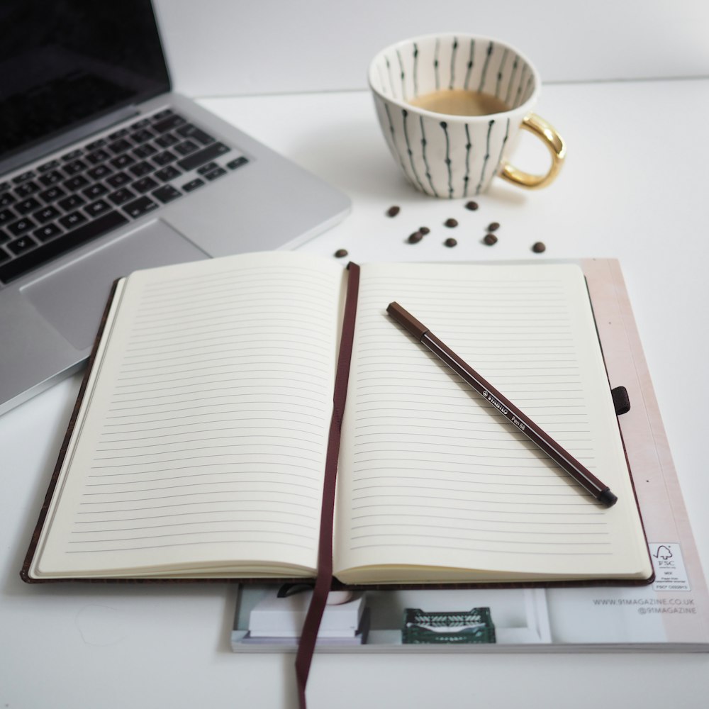 white notebook beside silver macbook pro