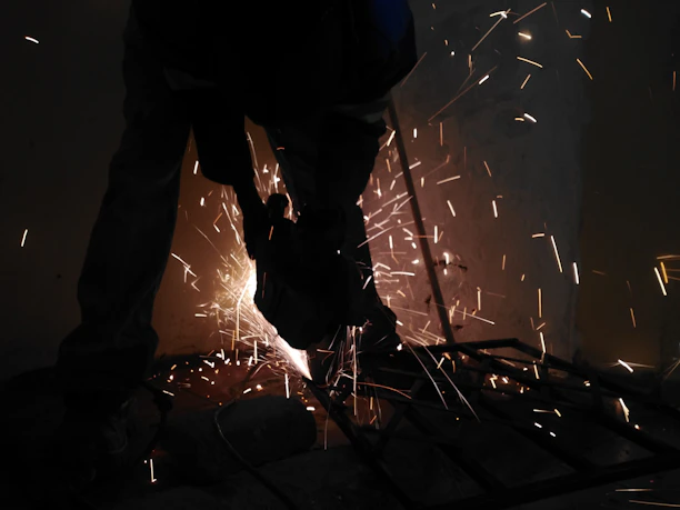 A worker operating a core cutting machine on a massive wooden log, sparks flying under dramatic industrial lighting.