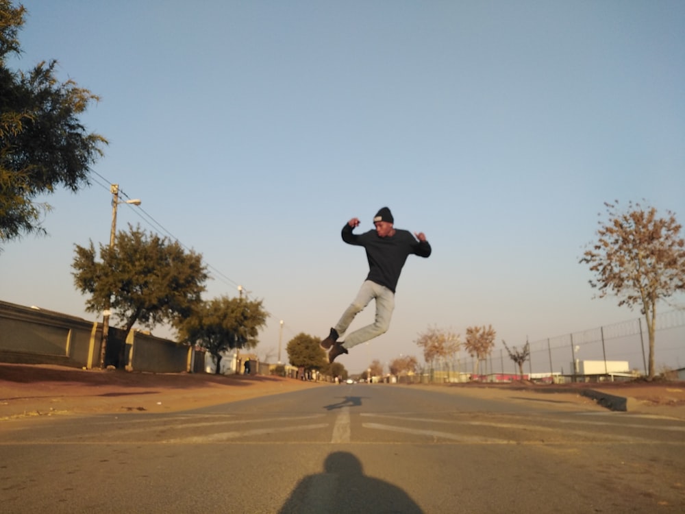 man in black t-shirt and black pants jumping on brown field during daytime