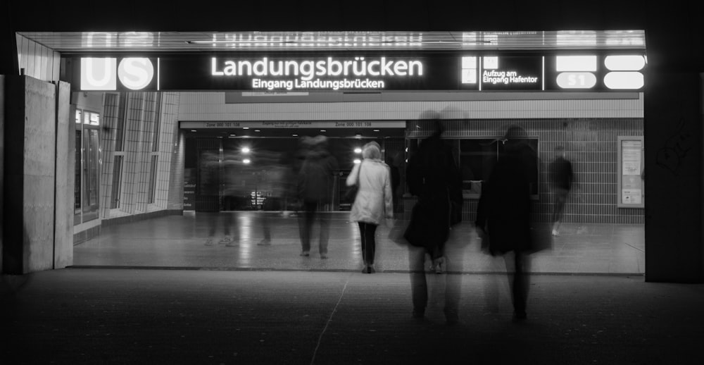 grayscale photo of people walking on train station