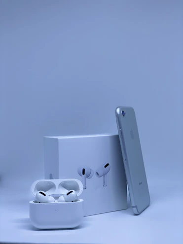 A sleek smartphone and wireless earbuds displayed on a clean white surface with soft blue and orange accents.