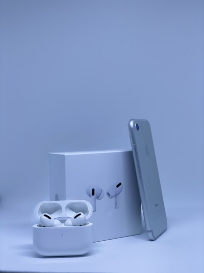 A sleek smartphone beside stylish wireless earbuds and charging cables on a clean white surface