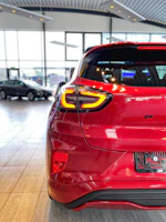 Red compact car displayed in a bright showroom with white and black accents