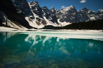 A crisp, wide-angle shot of a snow-capped Mount Temple reflected in a turquoise alpine lake under a clear sky.