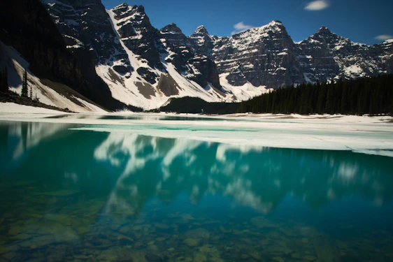 A crisp, wide-angle shot of a snow-capped Mount Temple reflected in a turquoise alpine lake under a clear sky.