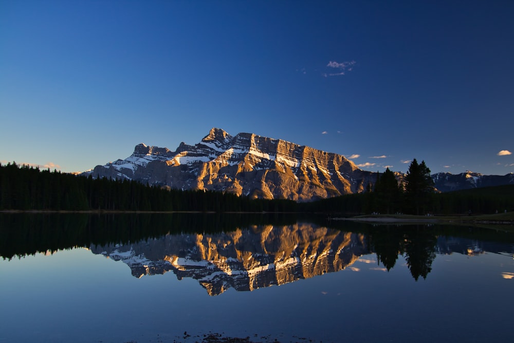 Montagna marrone e bianca vicino allo specchio d'acqua durante il giorno