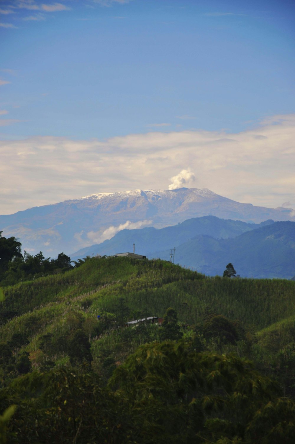 green grass field near mountain under white clouds during daytime