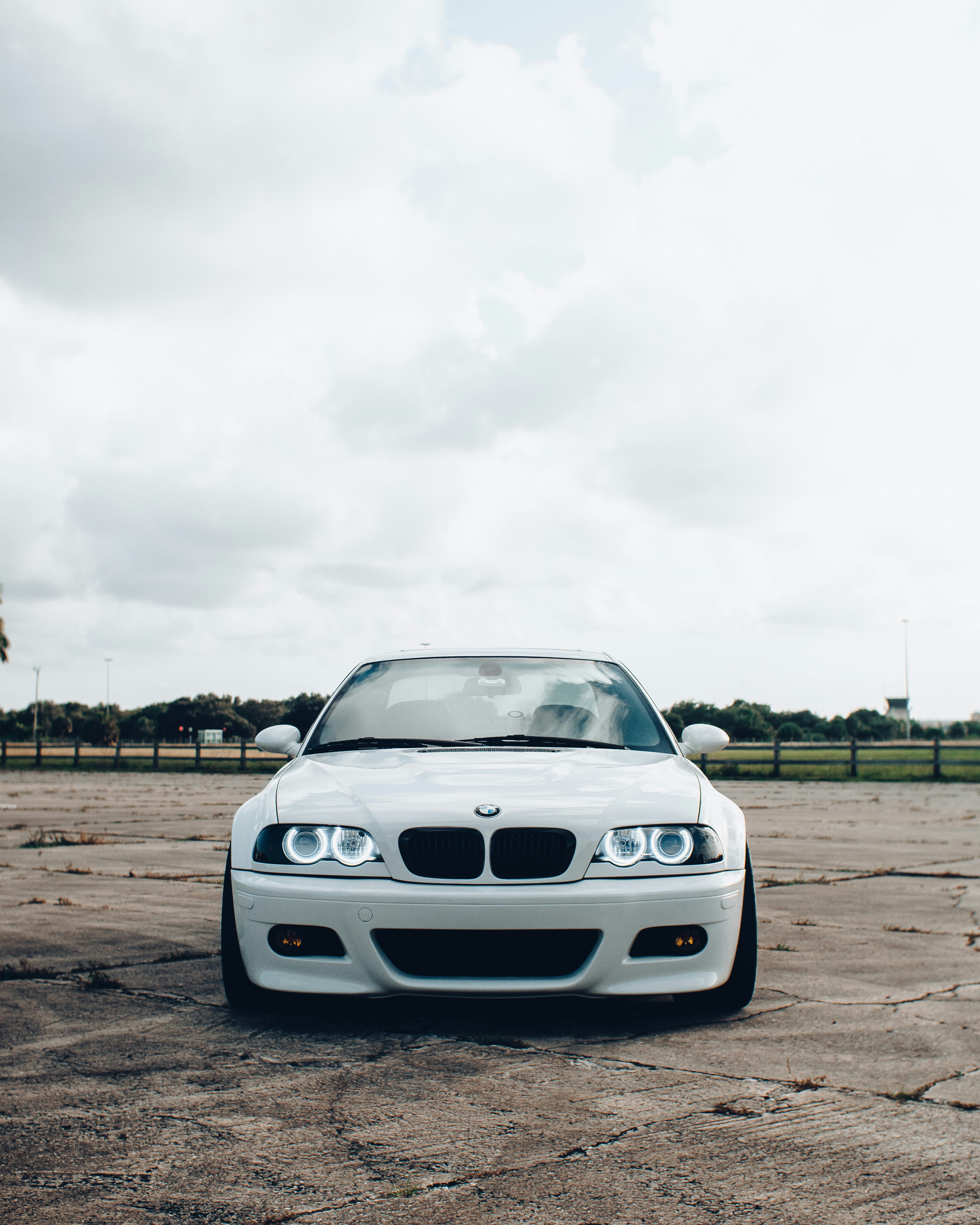 white bmw car on brown field under white cloudy sky during daytime