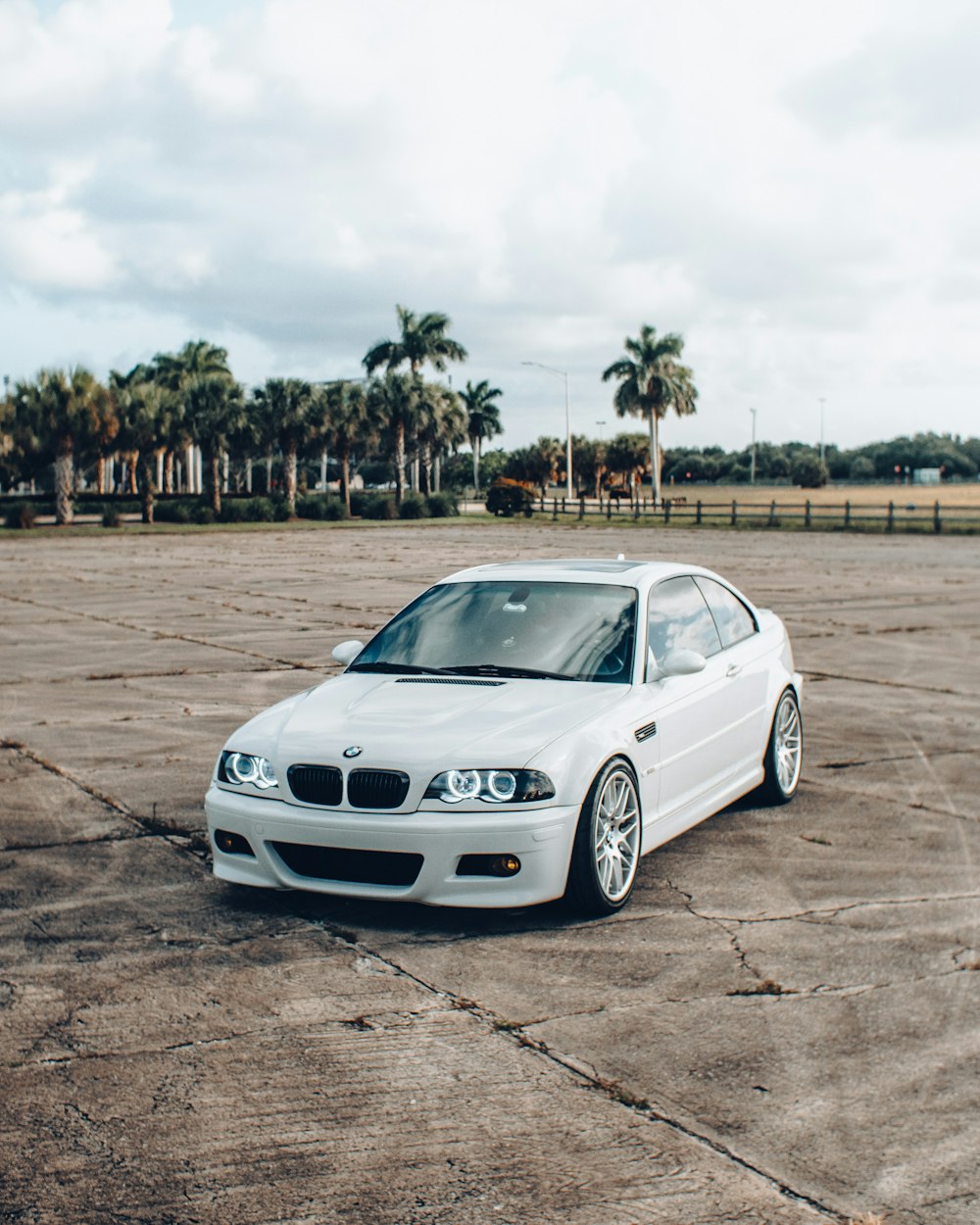 昼間の茶色の野原に白いBMW M3クーペ