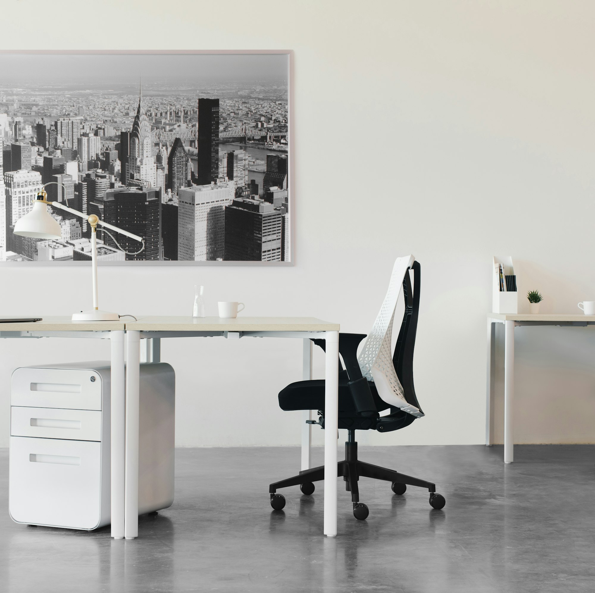 An open work space with a minimalist setup of chairs, tables, desks, and art.