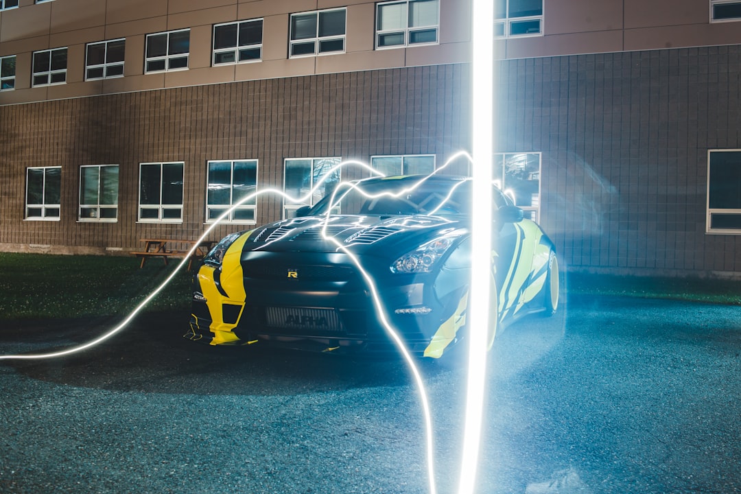 man in blue shirt and black pants standing beside yellow car