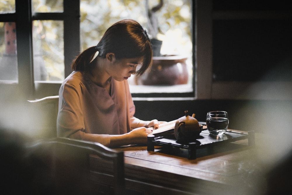 a woman sitting at a table writing on a piece of paper