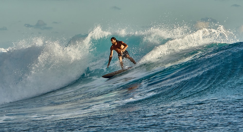 man in black shorts surfing on sea waves during daytime