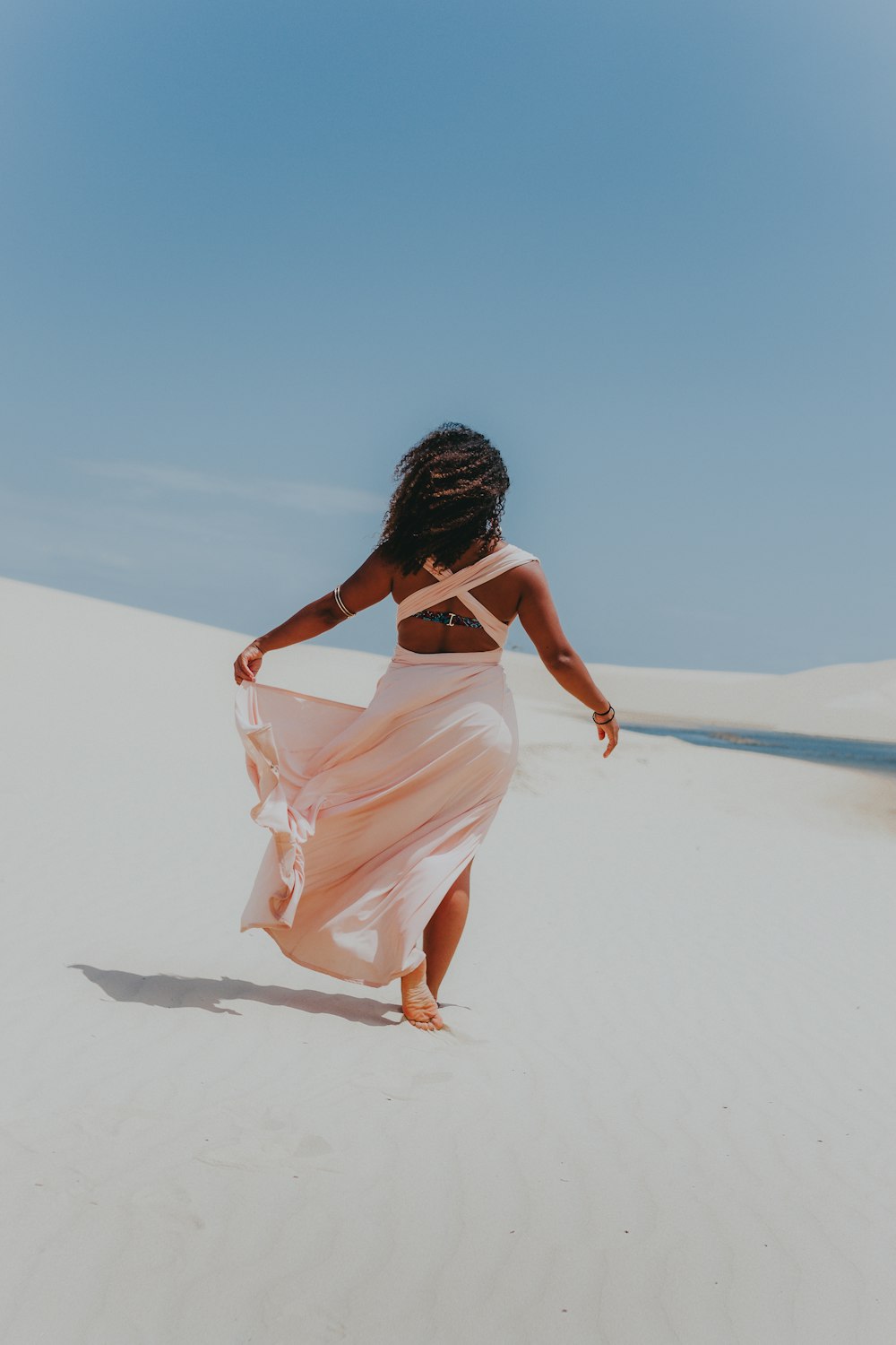 woman in white dress walking on sand during daytime