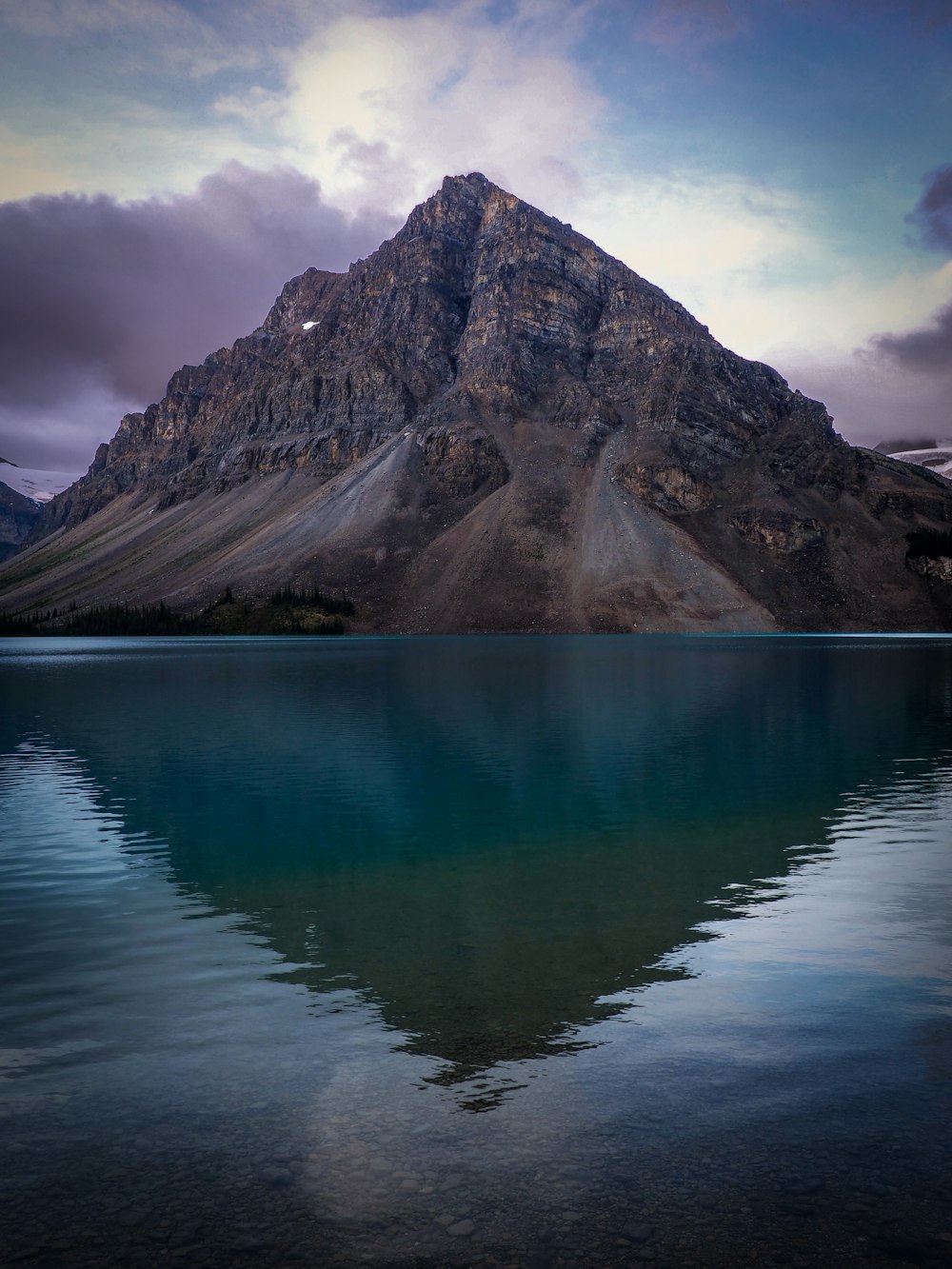 Lac près de la montagne sous ciel nuageux pendant la journée