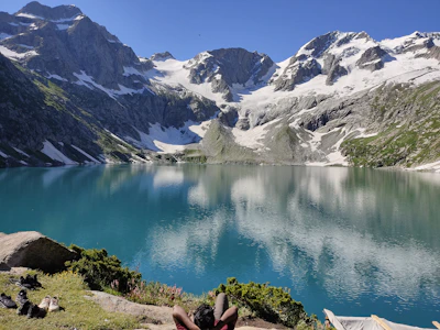 woman in black tank top sitting on brown wooden dock near lake during daytime