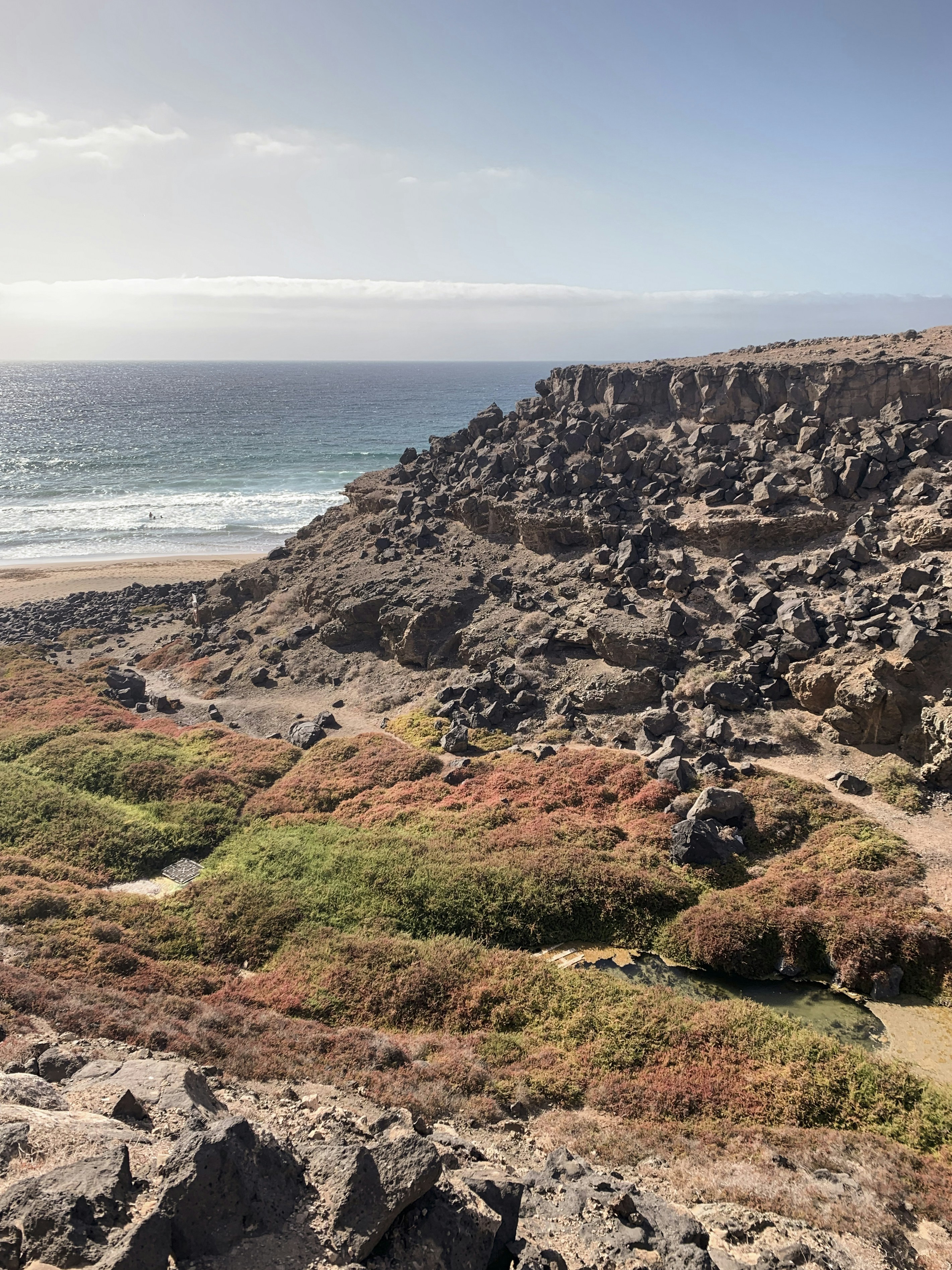 brown and green mountain beside sea during daytime