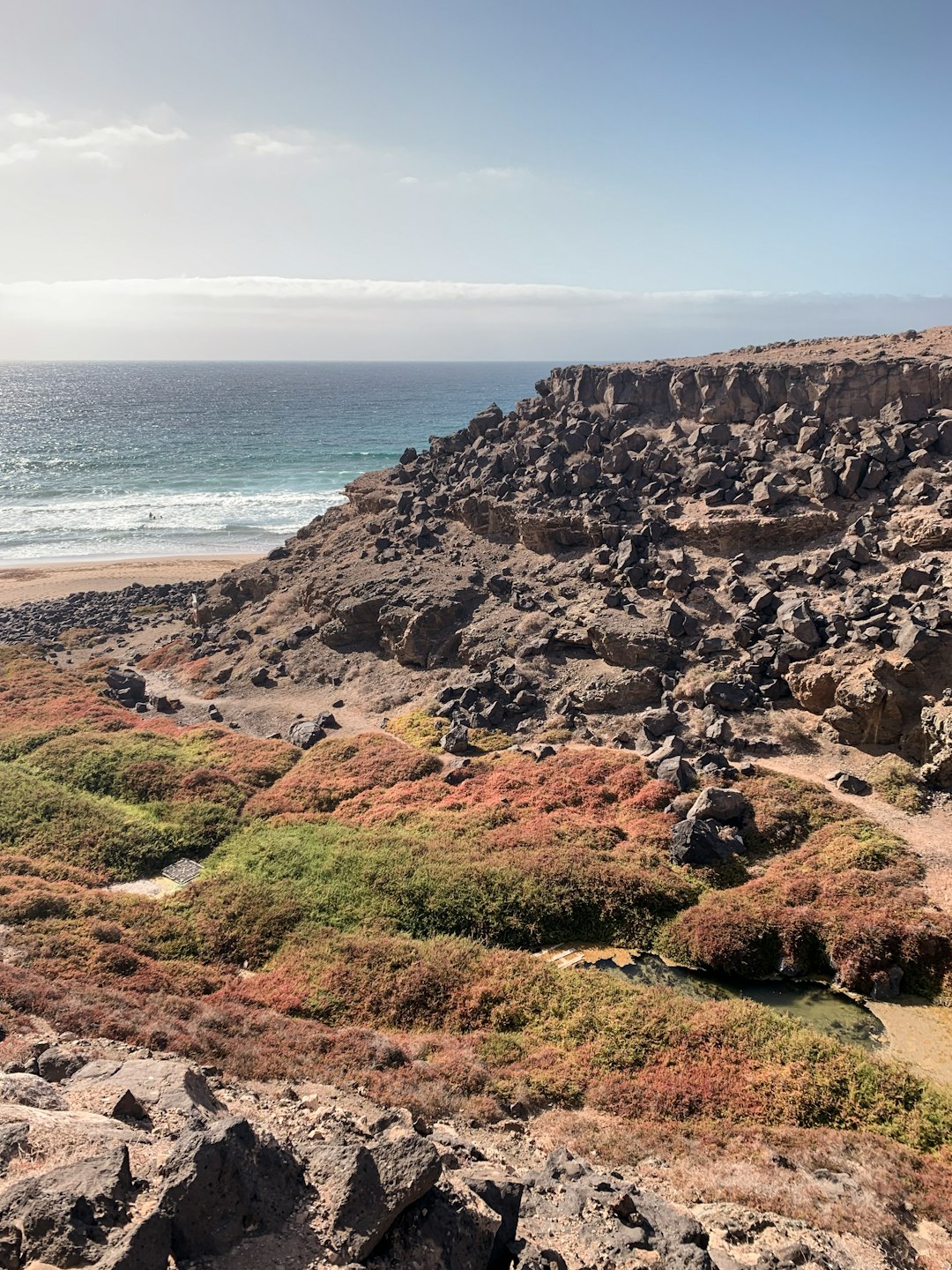 brown and green mountain beside sea during daytime