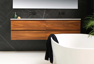 white ceramic bathtub near brown wooden cabinet