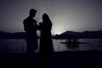 A romantic couple enjoying a serene sunset by a mountain lake in Pakistan.