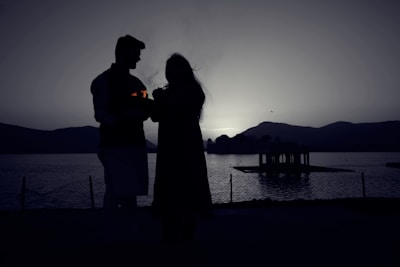 A romantic couple enjoying a serene sunset by a mountain lake in Pakistan.