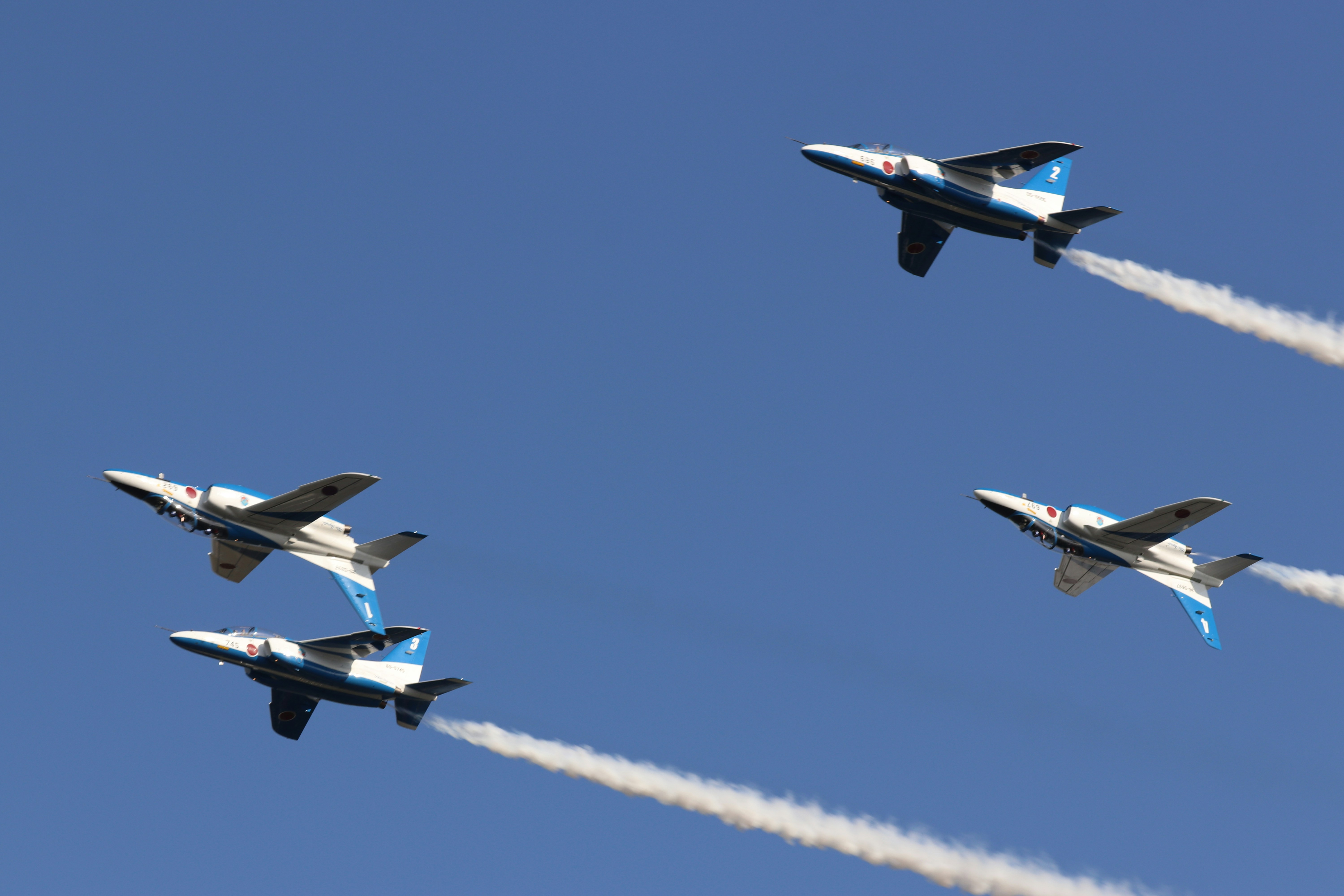 white and blue jet plane in mid air during daytime