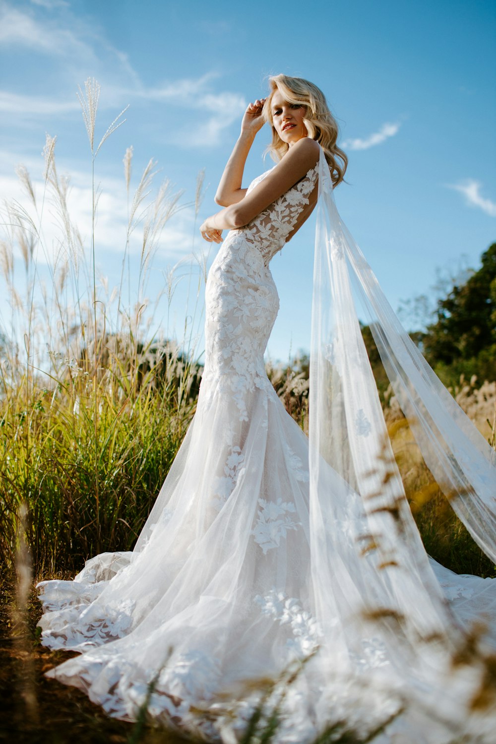 woman in white wedding dress standing on green grass field during daytime