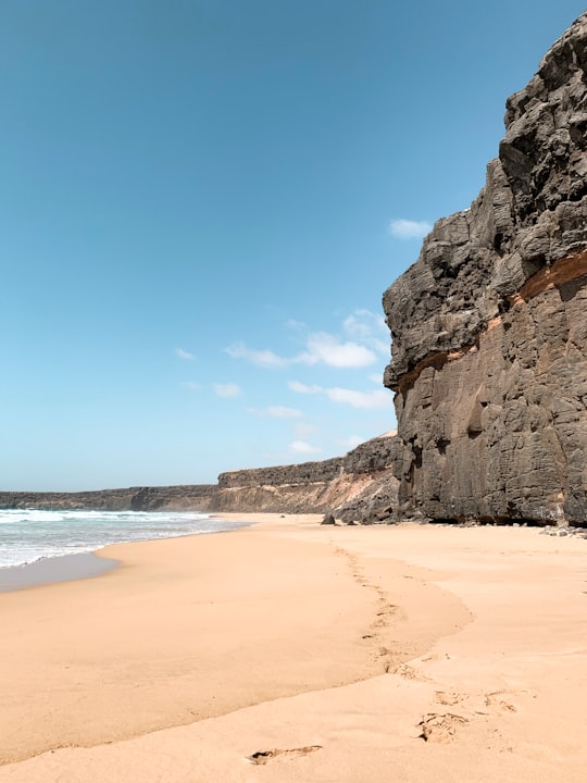 brown rock formation near body of water during daytime in Fuerteventura Spain