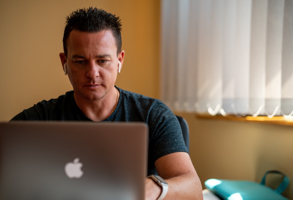 man in blue crew neck t-shirt using silver macbook