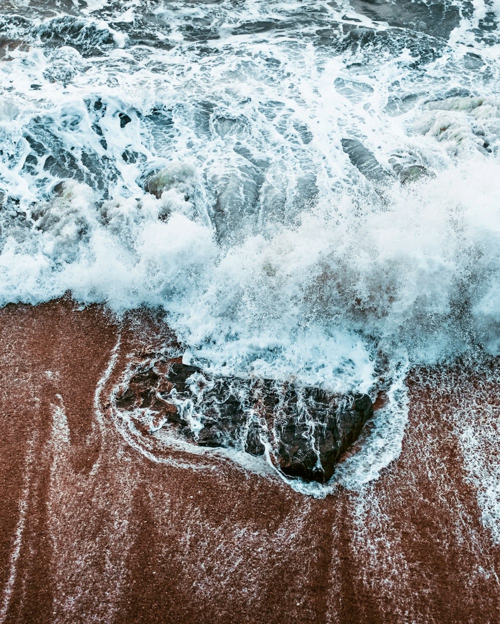 ocean waves crashing on brown sand