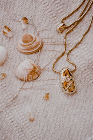 Bohemian-style accessories with seashell details displayed on a rustic wooden table by the sea.