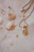 Close-up of a delicate seashell necklace resting on a soft knitted scarf in coastal colors.