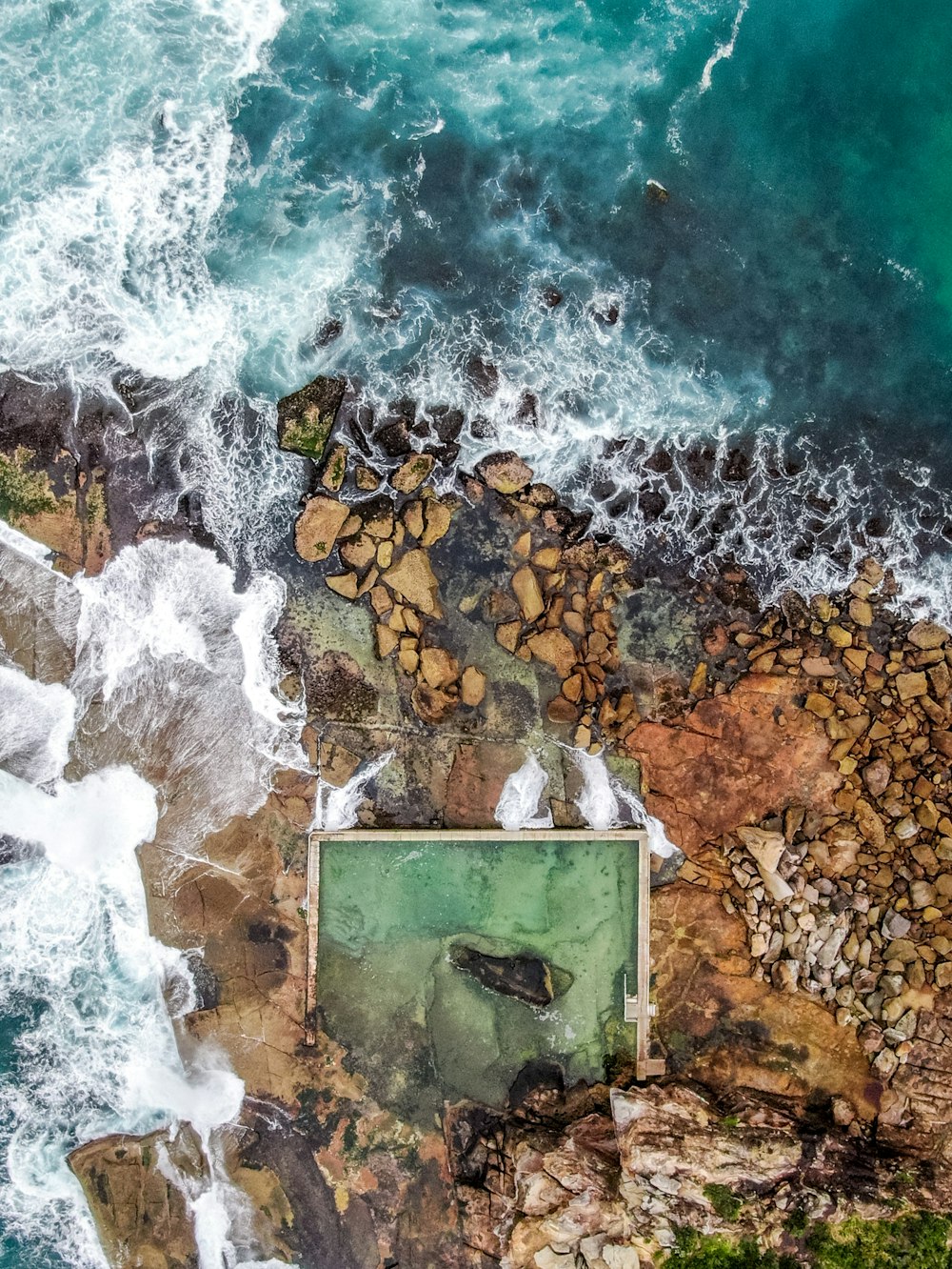 aerial view of ocean waves crashing on rocks during daytime
