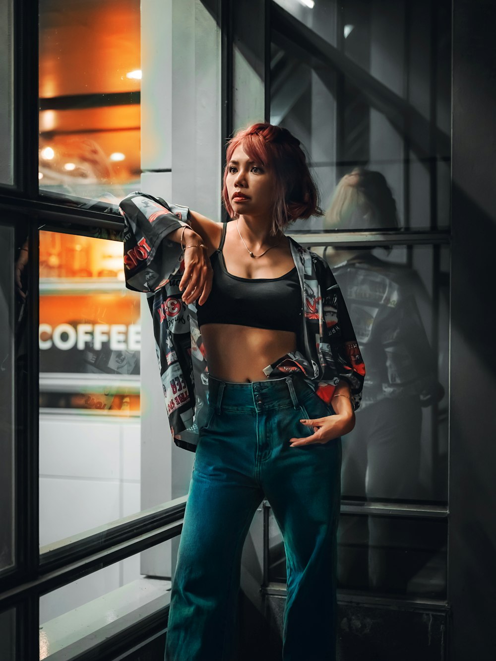 woman in black tank top and blue denim jeans standing beside glass window