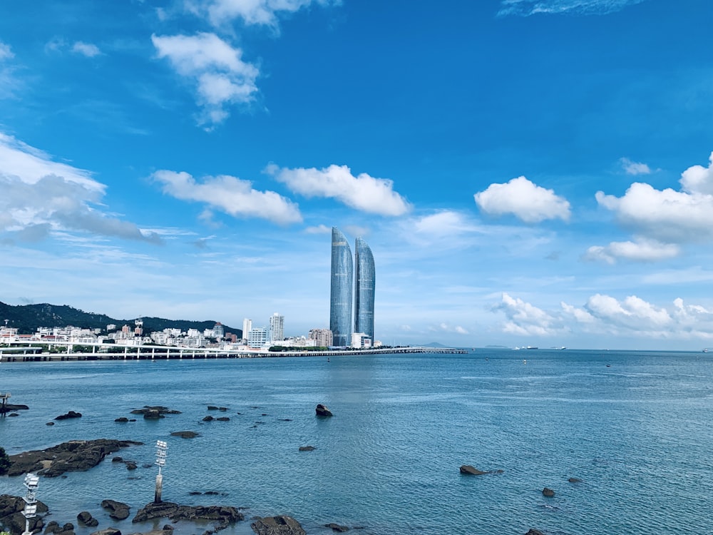 pessoas nadando no mar perto de edifícios da cidade sob céu nublado ensolarado azul e branco durante o dia