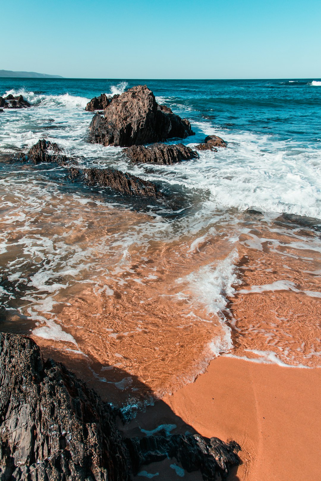 brown rocky shore with ocean waves during daytime