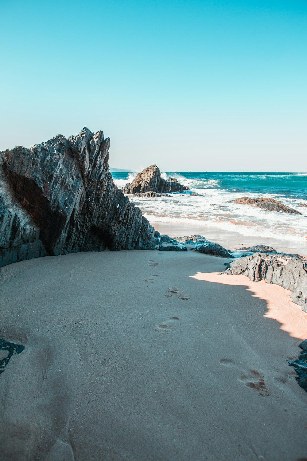 brown rocky mountain beside sea during daytime